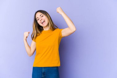 Mor arka planda soyutlanmış beyaz bir kadın tasasız ve heyecanlı bir şekilde tezahürat yapıyor. Zafer konsepti.