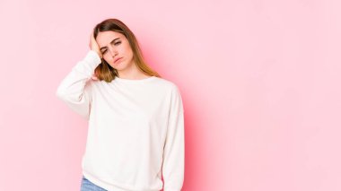 Pembe arka planda izole edilmiş genç beyaz kadın yorgun ve uykulu ellerini başının üstünde tutuyor..