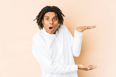 Genç Afro-Amerikan Rasta adamı ellerinin arasında bir kopya alanı tutarken şok oldu ve hayrete düştü..