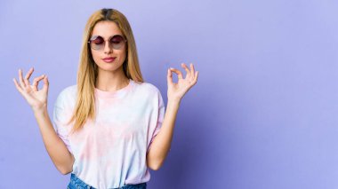 Mor arka planda gözlüklü genç hippi kadın sıkı çalışma gününden sonra rahatlıyor, yoga yapıyor..