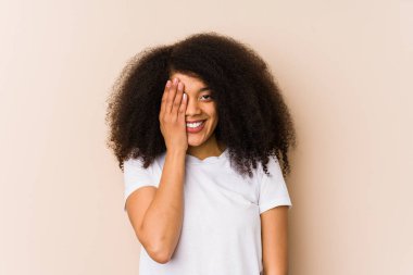 Genç Afro-Amerikalı kadın yüzünün yarısını avuç içiyle kaplayarak eğleniyor..