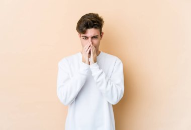 Kafkasyalı genç bir adam, bej arka planda izole edilmiş bir plan kuruyor, bir fikir kuruyor..