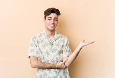 Beyaz, bej arka planda izole edilmiş genç bir adam bir avuç içinde fotokopi alanı ve belinde bir el daha gösteriyor..