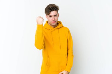 Beyaz arka planda izole edilmiş genç beyaz bir adam yumruğunu kameraya gösteriyor, agresif bir yüz ifadesi..