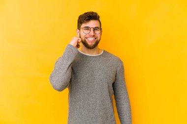 Sarı arka planda izole edilmiş genç beyaz adam zaferi, tutkuyu ve coşkuyu kutluyor, mutlu bir ifade..