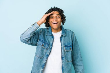 Kot ceket giyen genç siyah adam yüksek sesle bağırıyor, gözleri açık ve elleri gergin tutuyor..