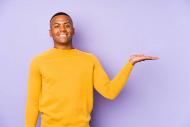 Mor arka planda izole edilmiş genç latin adam bir avuç içinde fotokopi alanı ve belinde bir el daha gösteriyor..