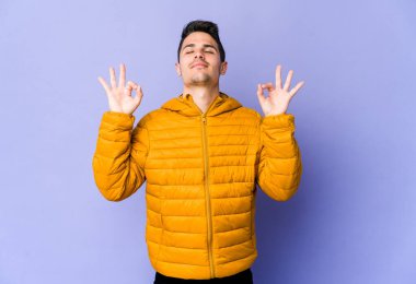 Mor arka planda izole edilmiş genç beyaz adam sıkı çalışma gününden sonra rahatlıyor. Yoga yapıyor..