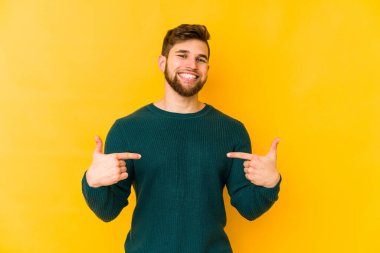 Sarı arka planda izole edilmiş genç beyaz adam parmakları aşağıda, olumlu bir his var..