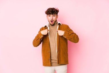 Pembe arka planda yalnız poz veren genç bir Arap.