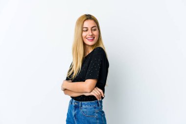 Beyaz arka planda soyutlanmış genç sarışın kadın kollarını kavuşturarak gülümsüyor..