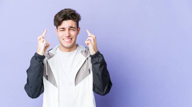 Mor arka planda izole genç beyaz adam şans dilemek için şans diliyor.