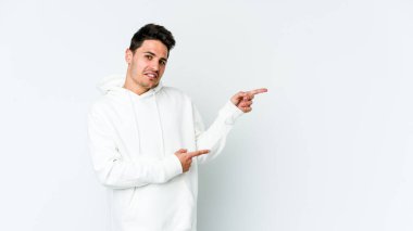 Beyaz arka planda izole edilmiş genç beyaz bir adam işaret parmağıyla fotokopi alanını işaret ederek şok oldu..