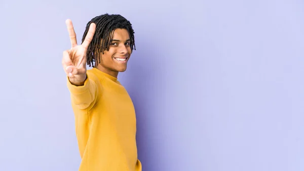 ラスタの髪型を身に着けている若い黒人男性喜びと屈託のない指で平和のシンボルを示す — ストック写真