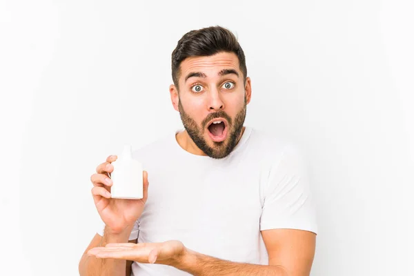 Joven Hombre Caucásico Sosteniendo Una Botella Vitaminas Aislado Impresionado Sosteniendo —  Fotos de Stock