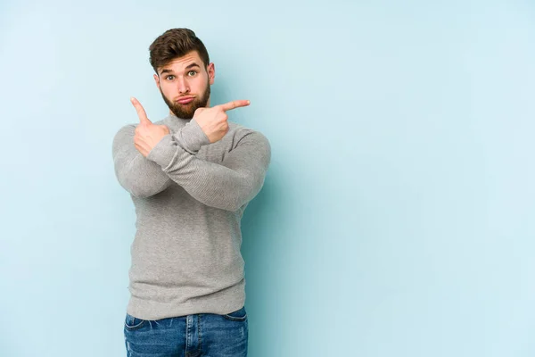 Jonge Blanke Man Geïsoleerd Blauwe Achtergrond Punten Zijwaarts Probeert Kiezen — Stockfoto