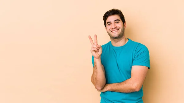 Junger Mann Auf Beigem Hintergrund Zeigt Nummer Zwei Mit Fingern — Stockfoto