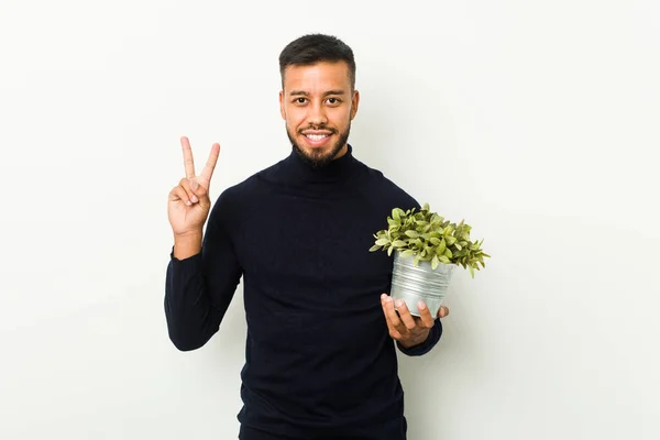 Ung Sydasiatisk Man Som Håller Planta Som Visar Nummer Två — Stockfoto