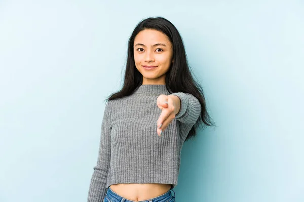 若いです中国人女性絶縁上の青い背景ストレッチング手でカメラでグリーティングジェスチャー — ストック写真
