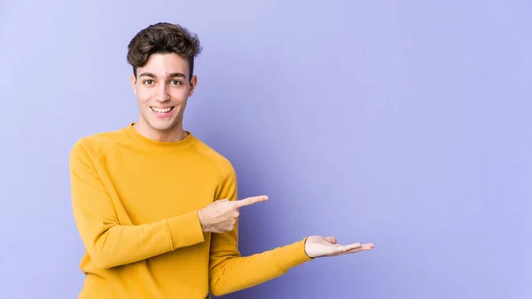 Jovem Caucasiano Isolado Fundo Roxo Animado Segurando Espaço Cópia Palma — Fotografia de Stock