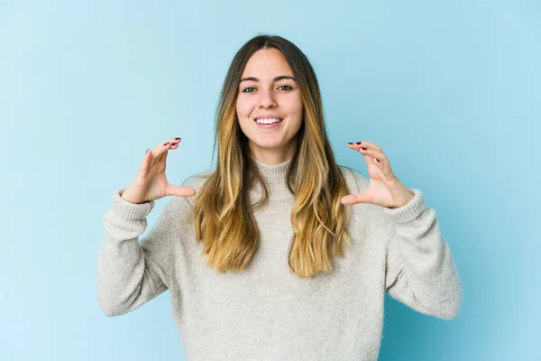 Jovem Caucasiana Isolado Fundo Azul Segurando Algo Com Palmas Das — Fotografia de Stock