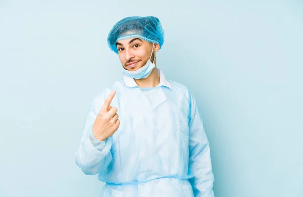 Homem Jovem Cirurgião Árabe Isolado Contra Fundo Azul Apontando Com — Fotografia de Stock