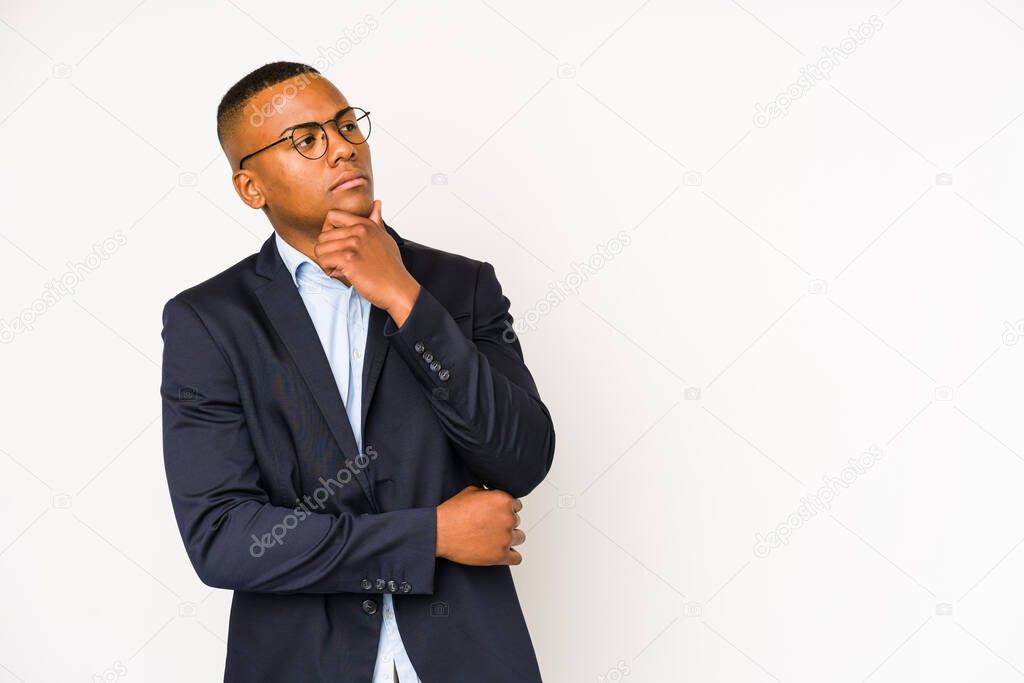 Young business latin man isolated on white background looking sideways with doubtful and skeptical expression.