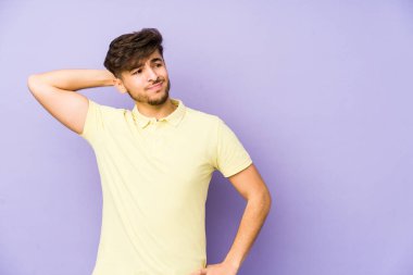 Mor arka planda soyutlanmış genç bir Arap adam kafasının arkasına dokunuyor, düşünüyor ve bir seçim yapıyor..