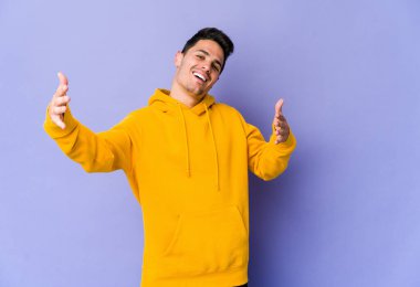 Mor arka planda izole genç beyaz adam kameraya sarıldığı için kendinden emin hissediyor..