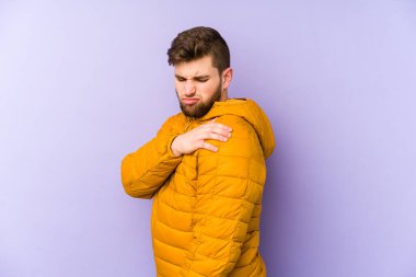 Mor arka planda, omuz ağrısı çeken genç bir adam..