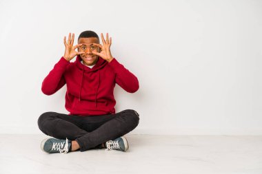 Yerde tek başına oturan genç latin adam bir başarı fırsatı bulmak için gözlerini açık tutuyor..