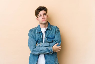 Beyazlı genç adam bej arka planda izole edilmiş. Tekrarlanan bir görevden yorulmuş..