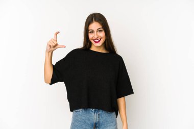 Beyaz arka planda izole edilmiş genç beyaz bir kadın. Elinde parmakları olan, gülümseyen ve kendinden emin bir şey tutuyor..