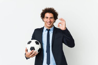 Futbol antrenörü elinde neşeli ve kendinden emin bir top tutuyor..