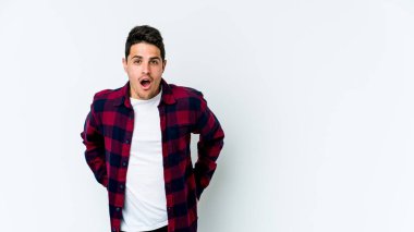 Beyaz arka planda izole edilmiş genç beyaz adam gördüğü bir şey yüzünden şoka uğruyor..