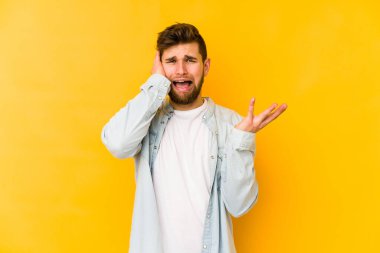 Sarı arka planda izole edilmiş genç beyaz adam öfkeyle bağırıyor..