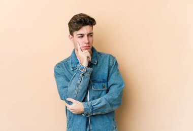 Beyazlı genç bir adam bej arka planda izole edilmiş. Bir strateji planlıyor, bir iş yolu düşünüyor..