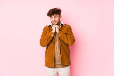 Pembe arka planda yalnız poz veren genç bir Arap.