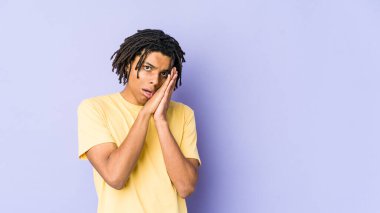 Genç Afrikalı Amerikalı Rasta adam esniyor. Ağzı eliyle kapatan yorgun bir jest gösteriyor..