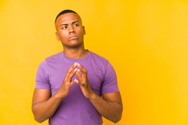 Genç latin adam sarı arka planda izole edildi. Aklında bir plan oluşturdu, bir fikir oluşturdu..