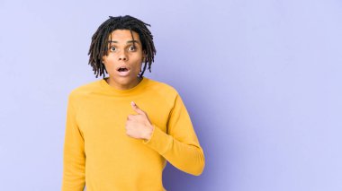 Rasta saç stili giyen genç siyahi adam parmağını göstererek şaşırdı, geniş bir gülümsemeyle..