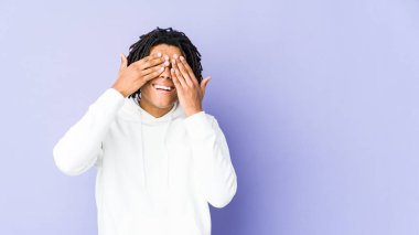 Genç Afrikalı Amerikalı Rasta adam elleriyle gözlerini kapatıyor, gülümseyerek bir sürpriz bekliyor..
