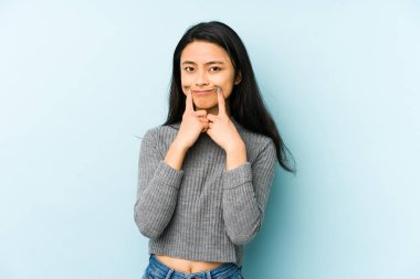 Genç Çinli bir kadın, mavi arka planda iki seçenek arasında şüpheli bir şekilde izole edilmiş..