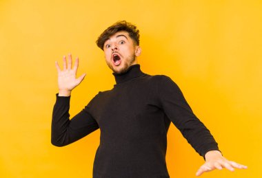 Sarı arka planda izole edilmiş genç bir Arap yakın bir tehlike nedeniyle şoka uğruyor.