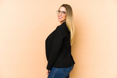 Orta yaşlı iş kadını bej arka planda izole edilmiş. Gülümsüyor, neşeli ve hoş görünüyor..