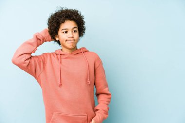 Afrika kökenli Amerikalı küçük çocuk kafasının arkasına dokunup düşünüyor ve bir seçim yapıyor..