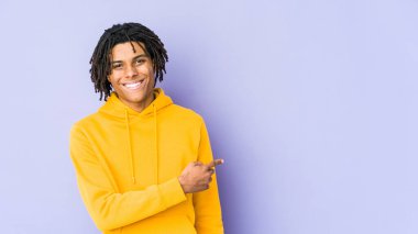 Genç Afrikalı Amerikalı Rasta adam gülümsüyor ve boş alanda bir şey gösteriyor..