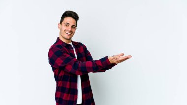 Beyaz arka planda izole edilmiş beyaz tenli genç bir adam palmiyesinde bir kopya alanı tutuyor..