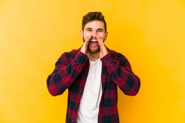 Sarı arka planda izole edilmiş genç beyaz bir adam bir dedikodu söylüyor, bir haber sunuyor..