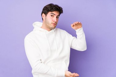 Mor arka planda izole genç bir adam iki eliyle bir şey tutuyor, ürün sunumu..